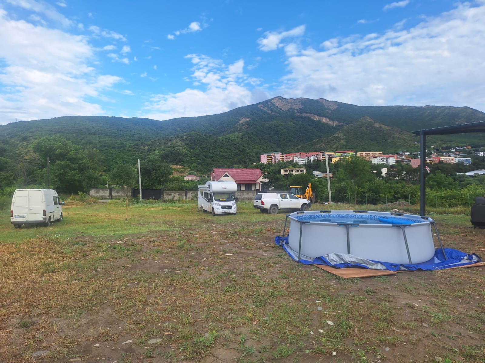 Campervans parked across a broad field below green mountains